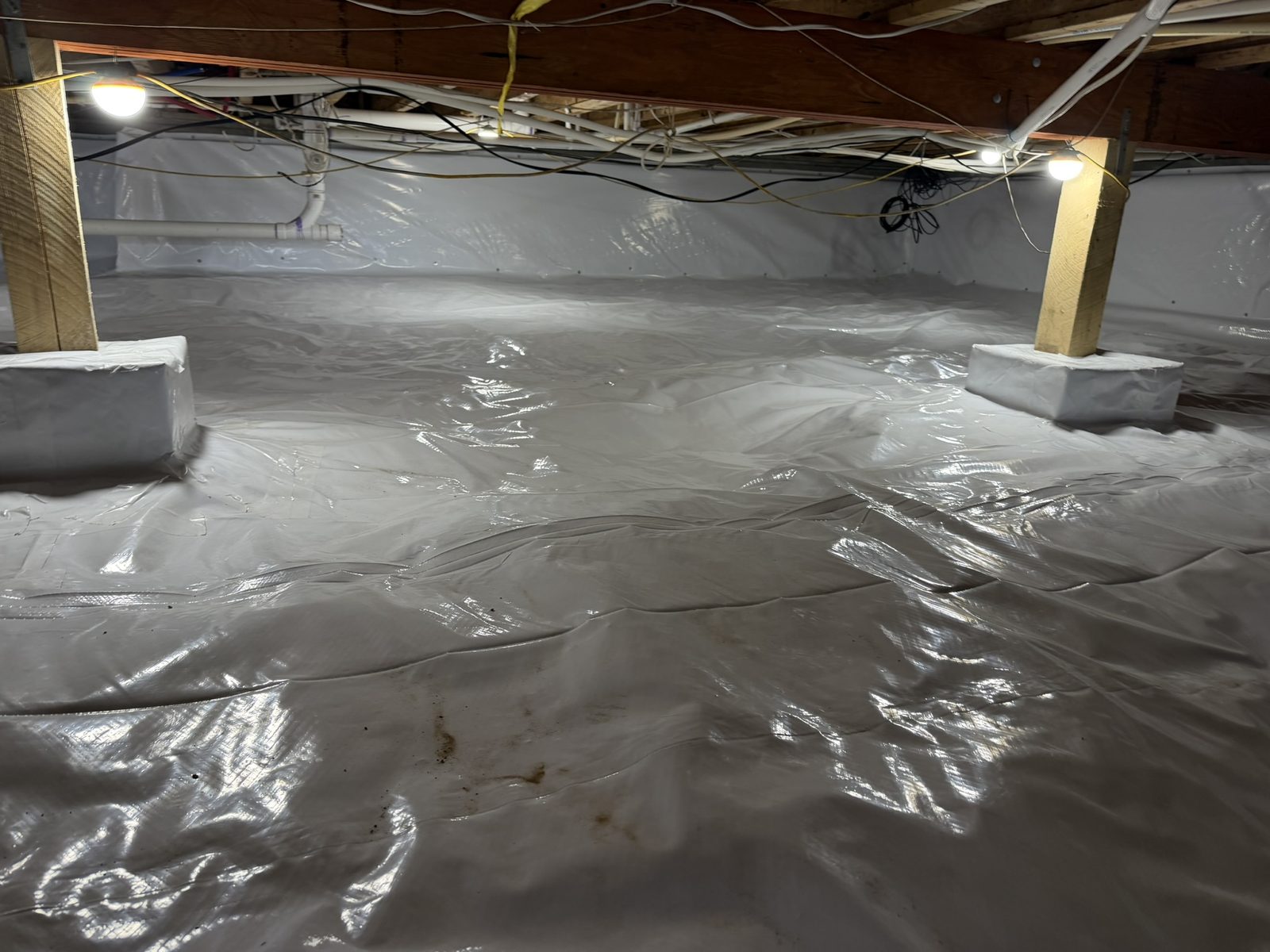 Encapsulated crawl space after installation of 12-mil string-reinforced vapor barrier across the floor and foundation walls