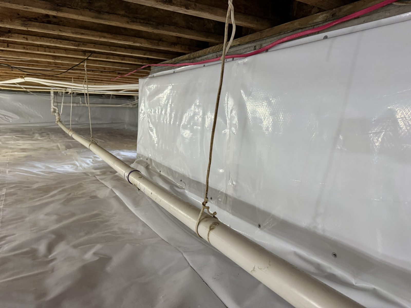Close-up of 12-mil crawl space wall liner mechanically fastened to the foundation with sealed seams